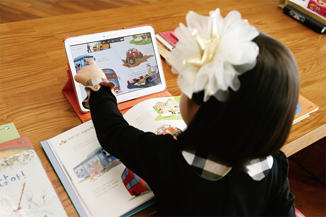웅진북클럽 도서와 단말기를 학습에 이용하는 어린이의 모습. 사진 웅진씽크빅