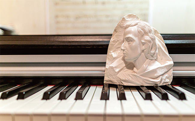프레데리크 쇼팽의 얼굴을 본뜬 조각물이 피아노 건반 위에 놓여 있다.