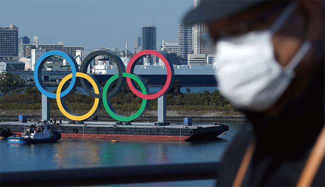 마스크를 쓴 일본인 남성 뒤로 올림픽 상징인 오륜이 보인다. AP연합