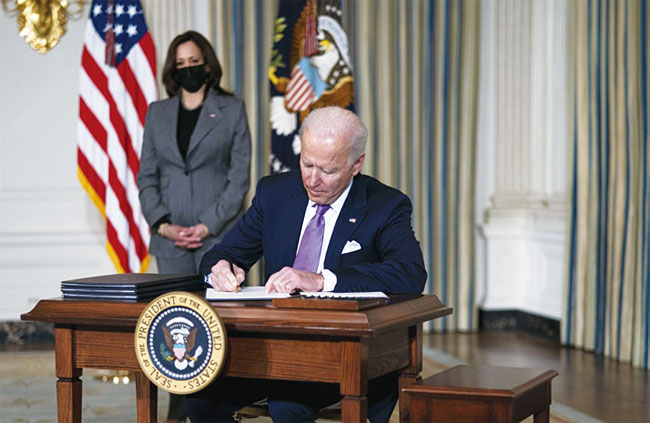 조 바이든 미국 대통령이 1월 26일(현지시각) 백악관에서 카멀라 해리스 부통령이 지켜보는 가운데 인종 간 불평등 해소를 위한 행정명령에 서명하고 있다. 사진 블룸버그