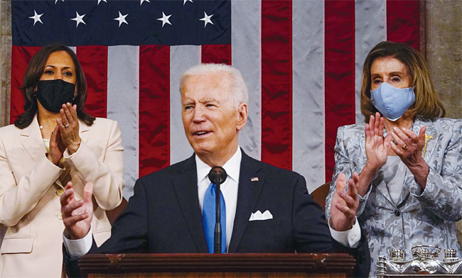 조 바이든 미국 대통령이 4월 28일(현지시각) 미 의회에서 첫 상·하원 합동연설을 하고 있다. 바이든 대통령 뒤에 미국 최초 여성이자 유색인종으로 2인자 자리에 오른 카멀라 해리스(왼쪽) 부통령과 낸시 펠로시 미 하원의장이 손뼉 치고 있다. 사진 블룸버그