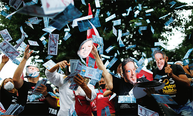 12월 8일(현지시각) 브라질 수도 브라질리아에서 자이르 보우소나루 대통령 등의 가면을 쓴 시위대가 복사 지폐를 뿌리며 물가 급등에 항의하는 시위를 벌이고 있다. 사진 연합뉴스