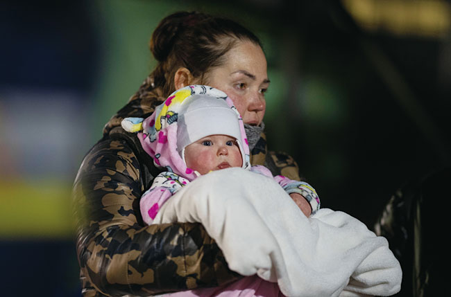 폴란드 남동부 도시 메디카에서한 우크라이나 여성이담요로 감싼 아기를 안고걸어서 국경을 넘고 있다. 사진 AP연합
