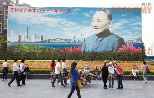 - 중국 광둥성 선전시 시민들이 덩샤오핑과 선전의 전경이 그려진 간판 앞을 지나가고 있다. 간판 왼쪽 위에는 ‘당의 기본 노선을 유지하며 100년 동안 흔들리지 말자’고 적혀 있다.