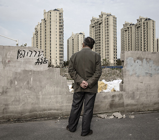 상하이의 한 시민이 건축 중인 아파트를 멀리 쳐다보고 있다.