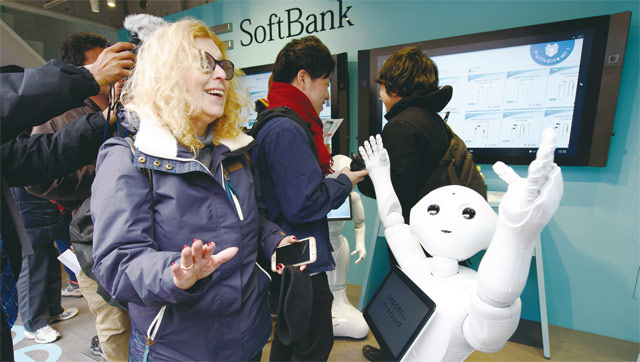 일본 통신업체 소프트뱅크의 도쿄 매장에서 한 고객이 소프트뱅크가 개발한 인공지능(AI) 로봇 ‘페퍼’의 안내를 받고 있다. <사진 : 블룸버그>