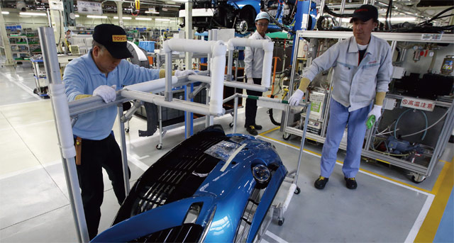 일본 도요타자동차 생산직 근로자들이 공장에서 수소 연료 전지차 ‘미라이’의 전면부 범퍼를 옮기고 있다. <사진 : 블룸버그>