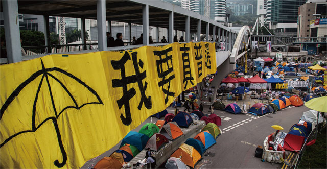 2014년 홍콩에서 일어난‘우산혁명’당시 금융 중심가 센트럴 일대를 점령한 시위대. 빌딩 사이를 잇는 육교에‘나는 직접·보통선거를 원한다’라는 현수막이 걸려 있다. <사진 : 블룸버그>