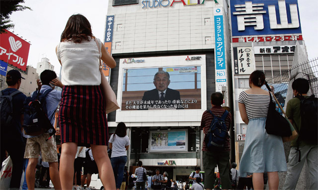 8일 오후 시민들이 도쿄 시내 전광판에 나오는 아키히토 일왕의 메시지를 보고 있다. <사진 : 연합뉴스 로이터>