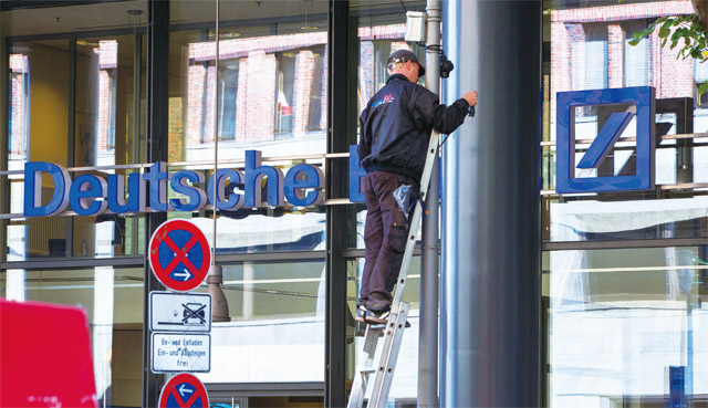 지난달 27일 독일 베를린에서 한 노동자가 도이체방크 지점 간판의 전선을 수리하고 있다. <사진 : 블룸버그>