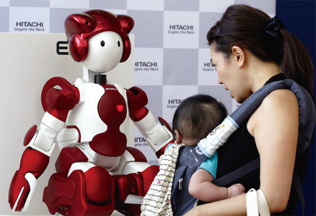 도쿄 하네다 공항 2터미널에 전시된 일본 히타치 신형 휴머노이드 로봇 에뮤3 모델을 아기를 안은 엄마가 보고 있다. 에뮤3 모델은 사람과 대화는 물론 신체적 상호작용이 가능하다. <사진 : 블룸버그>
