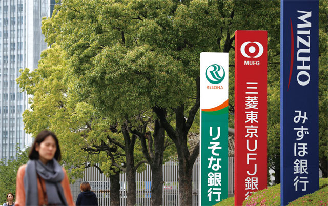 일본 도쿄에서 대형 은행인 미즈호은행, 미쓰비시도쿄UFJ은행, 리소나은행(오른쪽부터)의 간판 앞을 행인이 지나가고 있다. <사진 : 블룸버그>