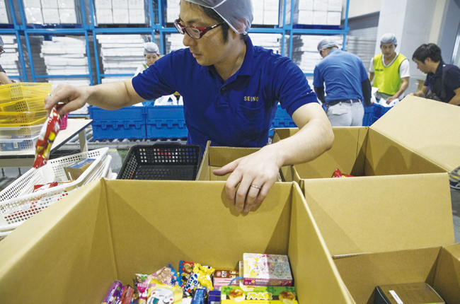 일본의 한 공장에서 노동자들이 종이상자에 식료품을 넣어 포장하고 있다. 사진 블룸버그