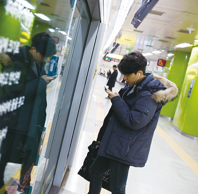 지하철을 기다리며 스마트폰으로 영상을 보는 시민. 사진 블룸버그