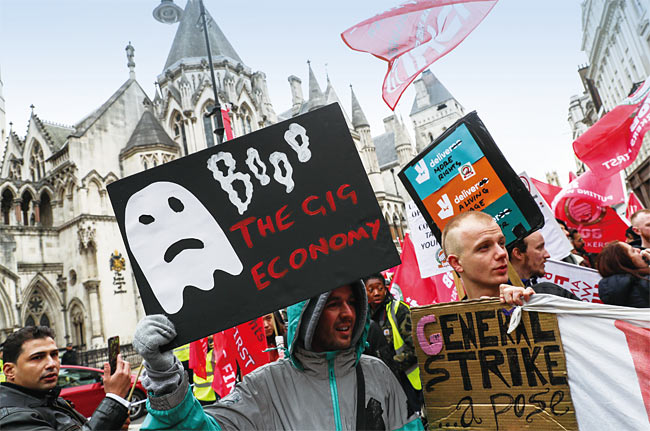 지난해 10월 영국에서 있었던 차량 공유 서비스 ‘우버’ 반대 시위. 시위 참가자가 ‘긱 이코노미 반대’라고 쓴 검은색 판넬을 들고 서있다. 사진 블룸버그