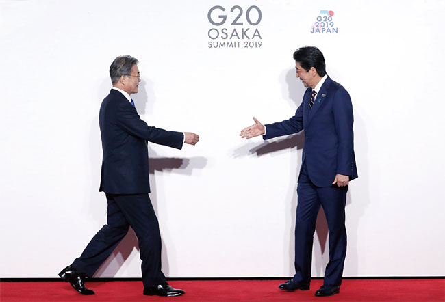 문재인 대통령이 6월 28일 일본 오사카에서 열린 주요 20개국(G20) 정상회의 공식 환영식에서 의장국인 일본 아베 신조 총리와 악수하기 위해 이동하고 있다. 사진 연합뉴스