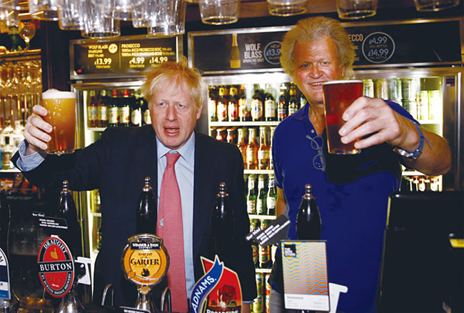 존슨 총리(왼쪽)가 외무장관이던 2018년 7월 10일 런던의 바에서 맥주를 마시고 있다. 그 옆은 팀 마틴 JD웨더스푼 회장이다. 사진 블룸버그