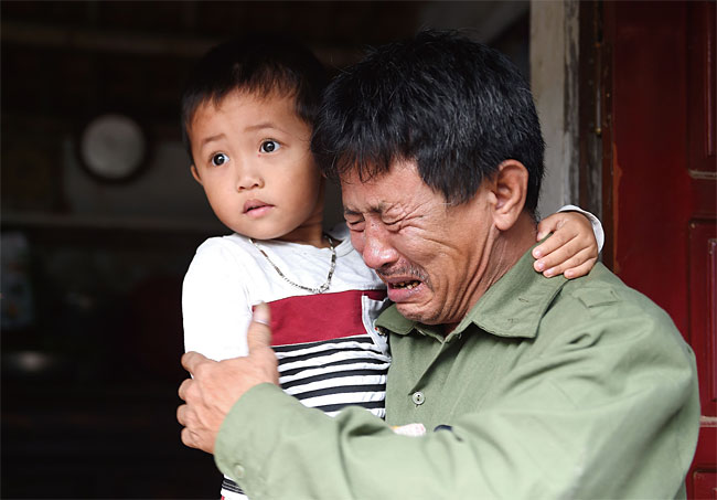 영국 냉동 컨테이너에서 숨진 채 발견된 39명 중 한 명으로 추정되는 르 반하(30)의 아버지 르 민 투안이 10월 27일 베트남 응에안성 집 앞에서 손자를 안고 울고 있다. 사진 AFP연합