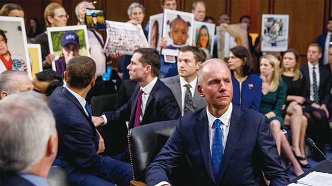 보잉 CEO가 미국 상원 위원회에 출석한 가운데, 사고 유족들이 사망자 사진을 들어 보이고 있다. 사진 AP연합