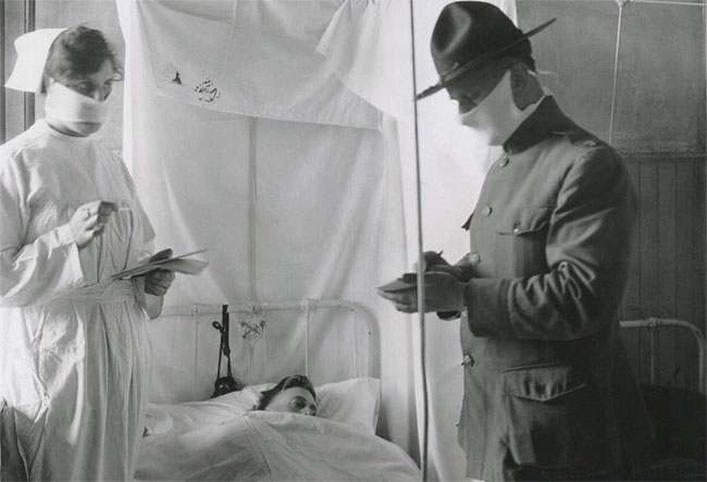 1918년 가을, 미국 매사추세츠주의 데븐스 병영에 있는 군병원에서 마스크를 착용한 의사와 간호사가 스페인 독감에 걸린 환자를 진찰하고 있다.