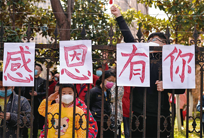 3월 18일 중국 후베이성 우한에서 주민들이 코로나19 복구 작업을 끝내고 돌아가는 의료진을 환송하고 있다. 사진 AFP연합