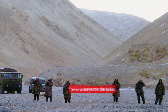 2013년 중국군이 인도 북부 라다크의 국경 지역에서 “당신은 국경을 넘었다. 돌아가라”고 쓰인 현수막을 들고 서 있다. 사진 AP연합