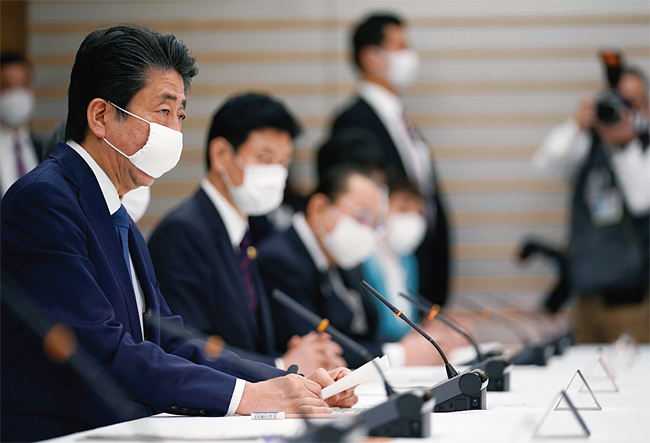 도쿄 총리관저에서 신종 코로나 바이러스 감염증(코로나19) 대책본부 회의를 주재하고 있는 아베 신조(왼쪽) 일본 총리. 사진 연합뉴스