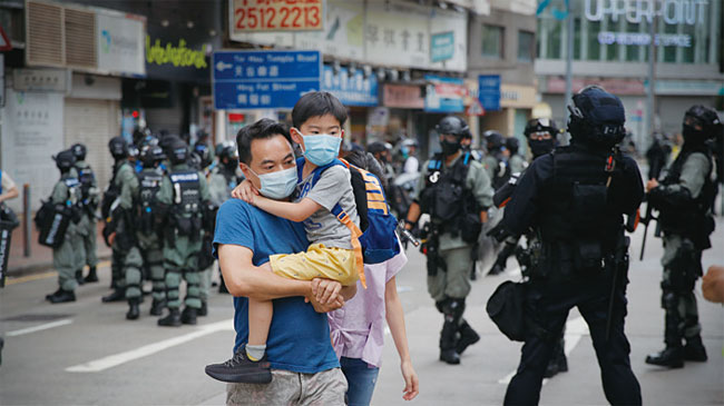 홍콩 반환 23주년 기념일인 7월 1일 한 남성이 아들을 안은 채 길을 건너고 있다. 사진 AP연합