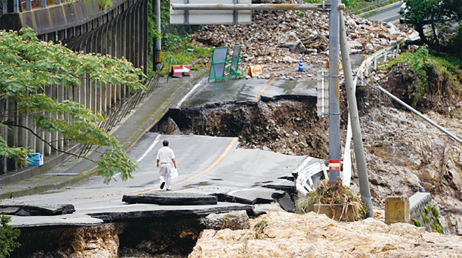 일본 서부 구마모토현에서 7월 6일 한 주민이 폭우로 무너져 내린 도로를 걷고 있다. 사진 연합뉴스