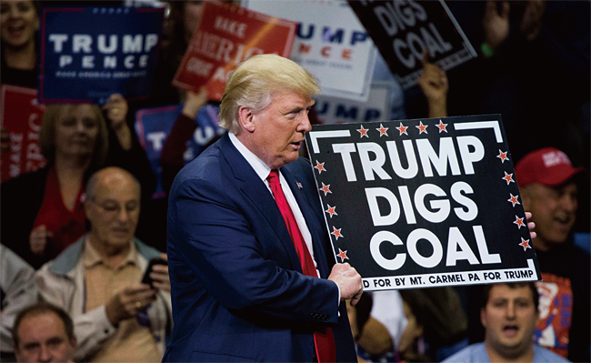 ‘트럼프는 석탄을 캔다(Trump Digs Coal)’란 문구가 적힌 팻말을 들고 있는 도널드 트럼프 미 대통령. 석탄 화력 발전 방식에 우호적이다. 사진 AFP연합