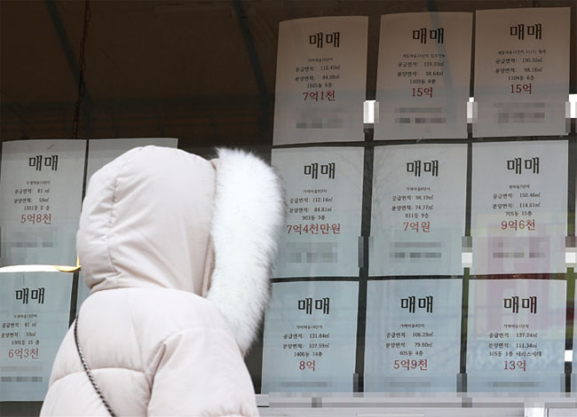 세종시의 한 공인중개소 유리창에 붙은 아파트 매매가격표를 한 시민이 바라보고 있다. 사진 연합뉴스