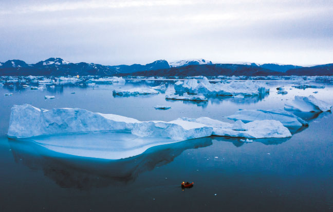 한 보트가 2019년 8월 15일 늦은 오후 그린란드 동부 쿨루수크 타운 부근의 빙하 옆을 지나가고 있다. 연구진에 따르면, 북극 아래 그린란드 빙상의 2001∼2011년 온도가 20세기 평균보다 섭씨 1.5도 올라가 1000년 이래 가장 높았던 것으로 나타났다. /AP연합